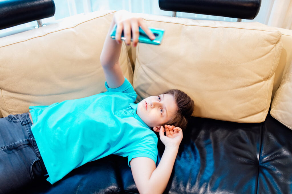 a boy glued to mobile while lying 